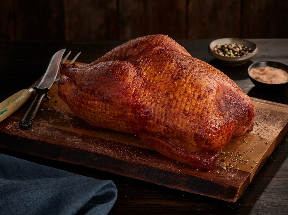 A SADLER'S SMOKEHOUSE® whole turkey on a cutting board with seasonings in the background.