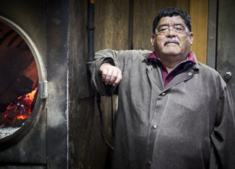 Pit master standing next to a smoker.