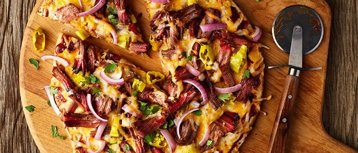 SADLER'S SMOKEHOUSE® brisket on a pizza with red onion and banana peppers.