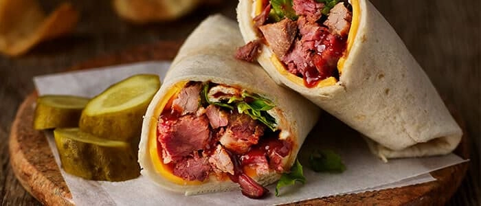 SADLER'S SMOKEHOUSE® brisket in a wrap with cheese, bbq sauce, and lettuce.