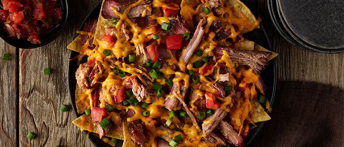 SADLER'S SMOKEHOUSE® brisket on nachos with melted cheese, green onion, and tomato.